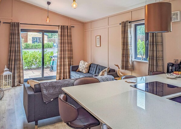 A modern living room with a sofa, a dining table, and a kitchen area.