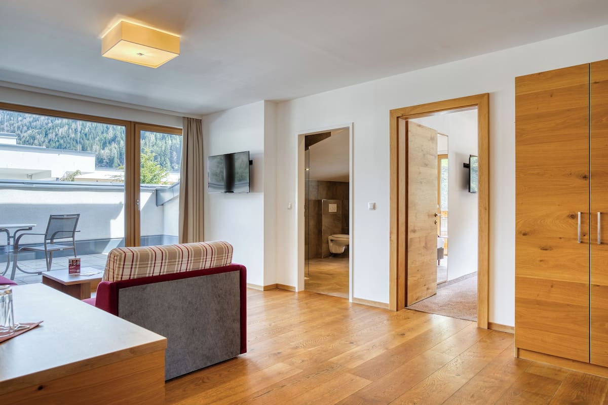 Suite Deluxe, 1 habitación | Área de sala de estar | Televisión de pantalla plana de 50 pulgadas con canales por cable