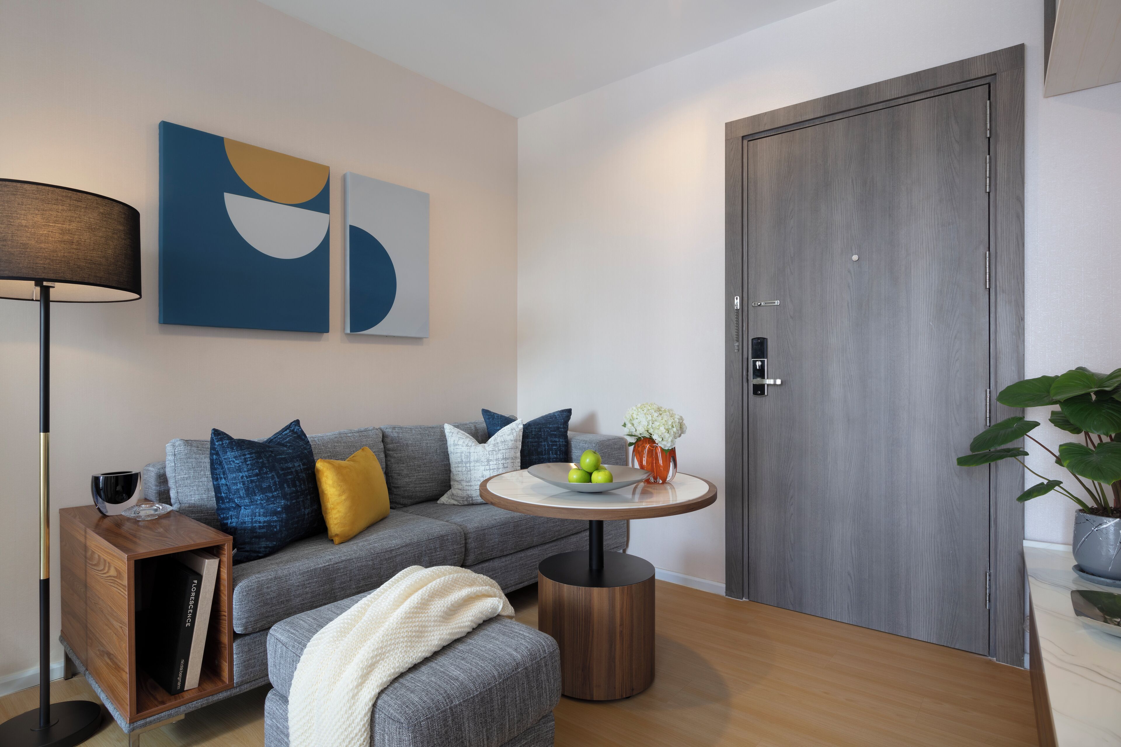 A modern living room with a grey sofa, a round wooden coffee table, and abstract wall art.