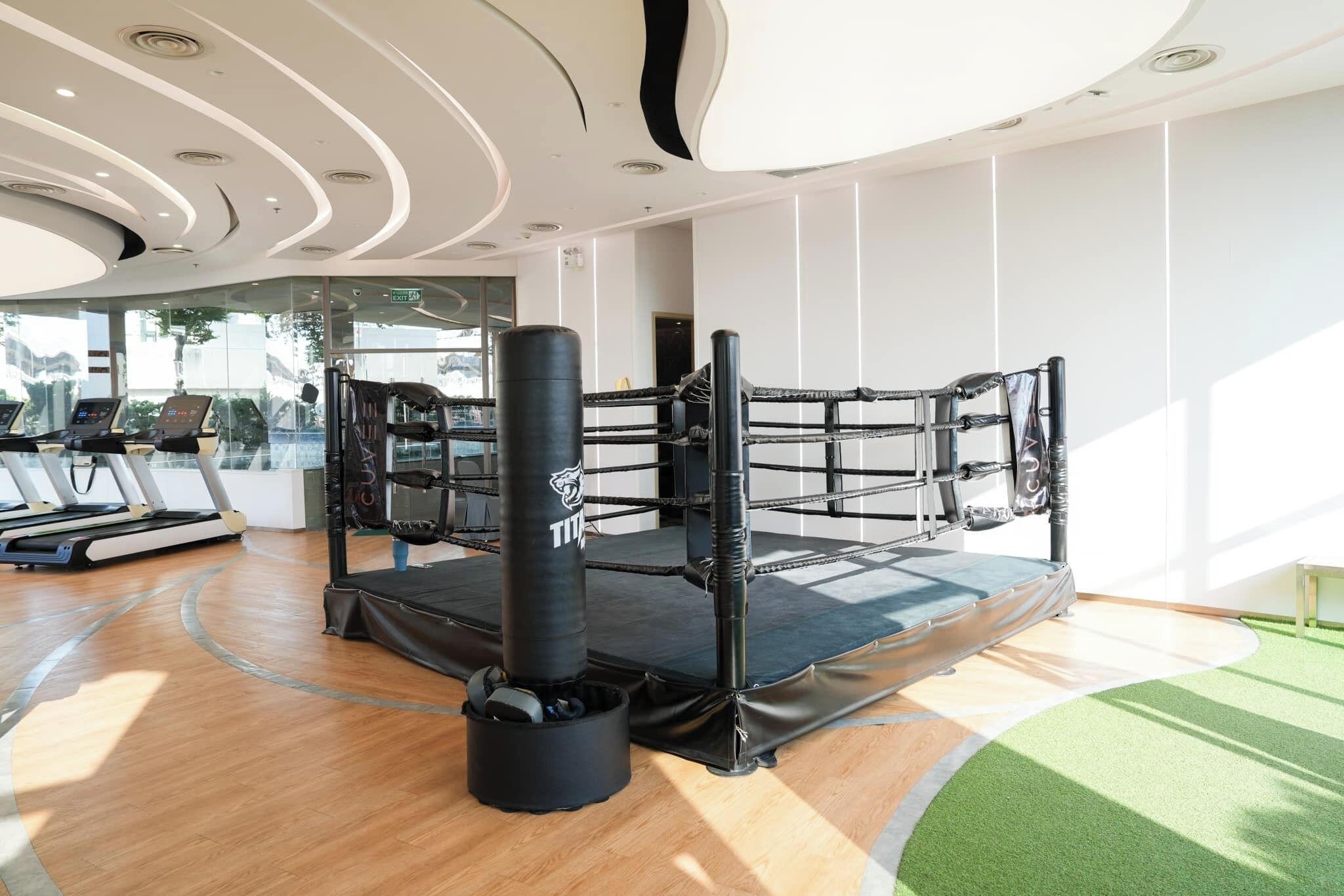 A modern gym with a boxing ring, treadmills, and a punching bag.