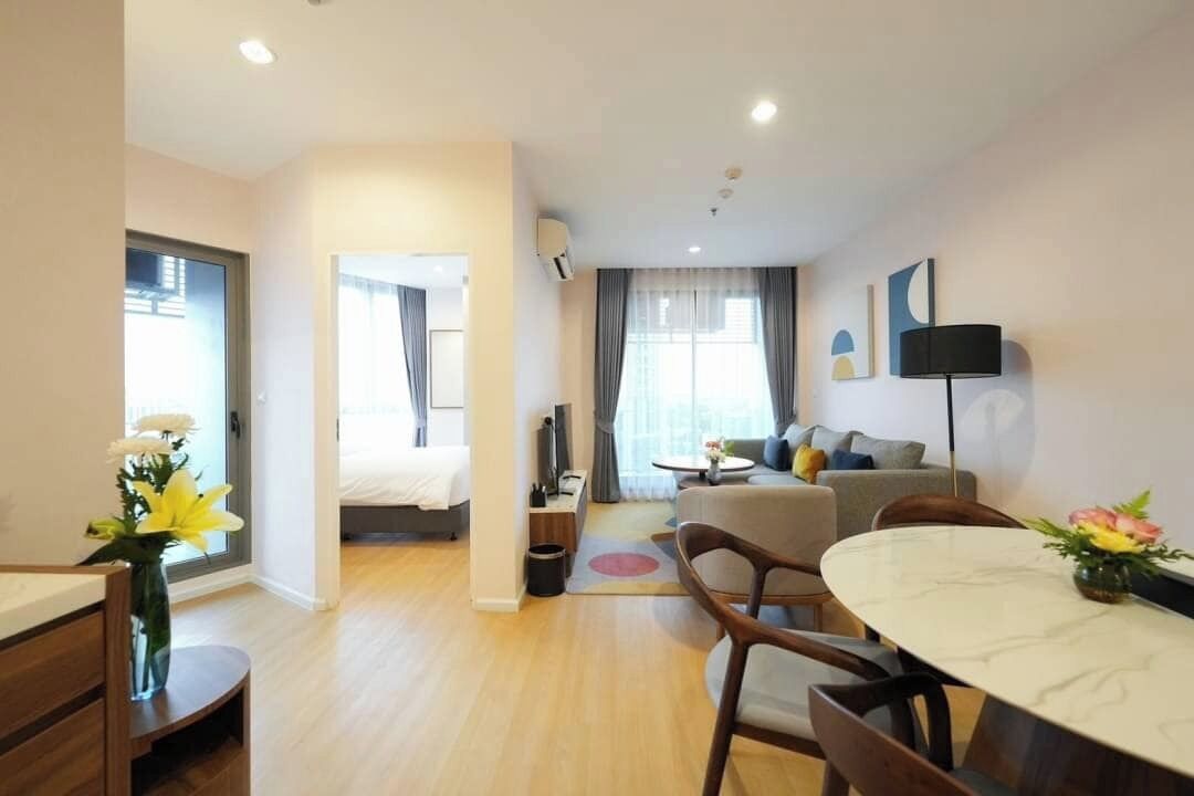A modern hotel room with a dining area, a sofa, and a TV.