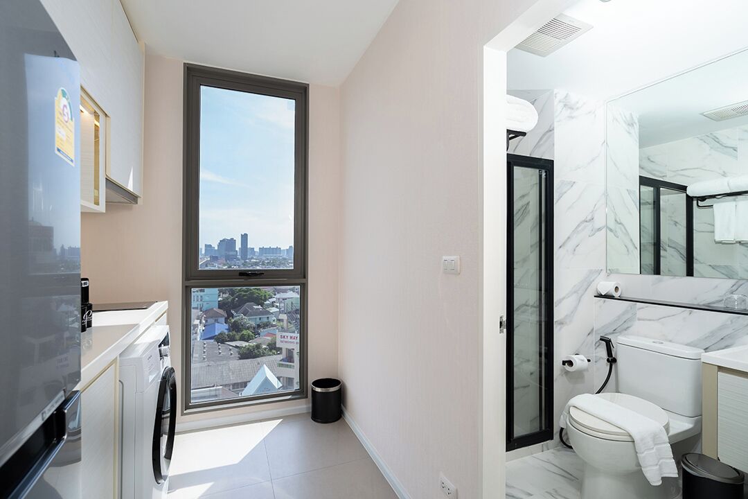 Une salle de bain moderne dotée d’une grande fenêtre, de toilettes et d’un espace douche.