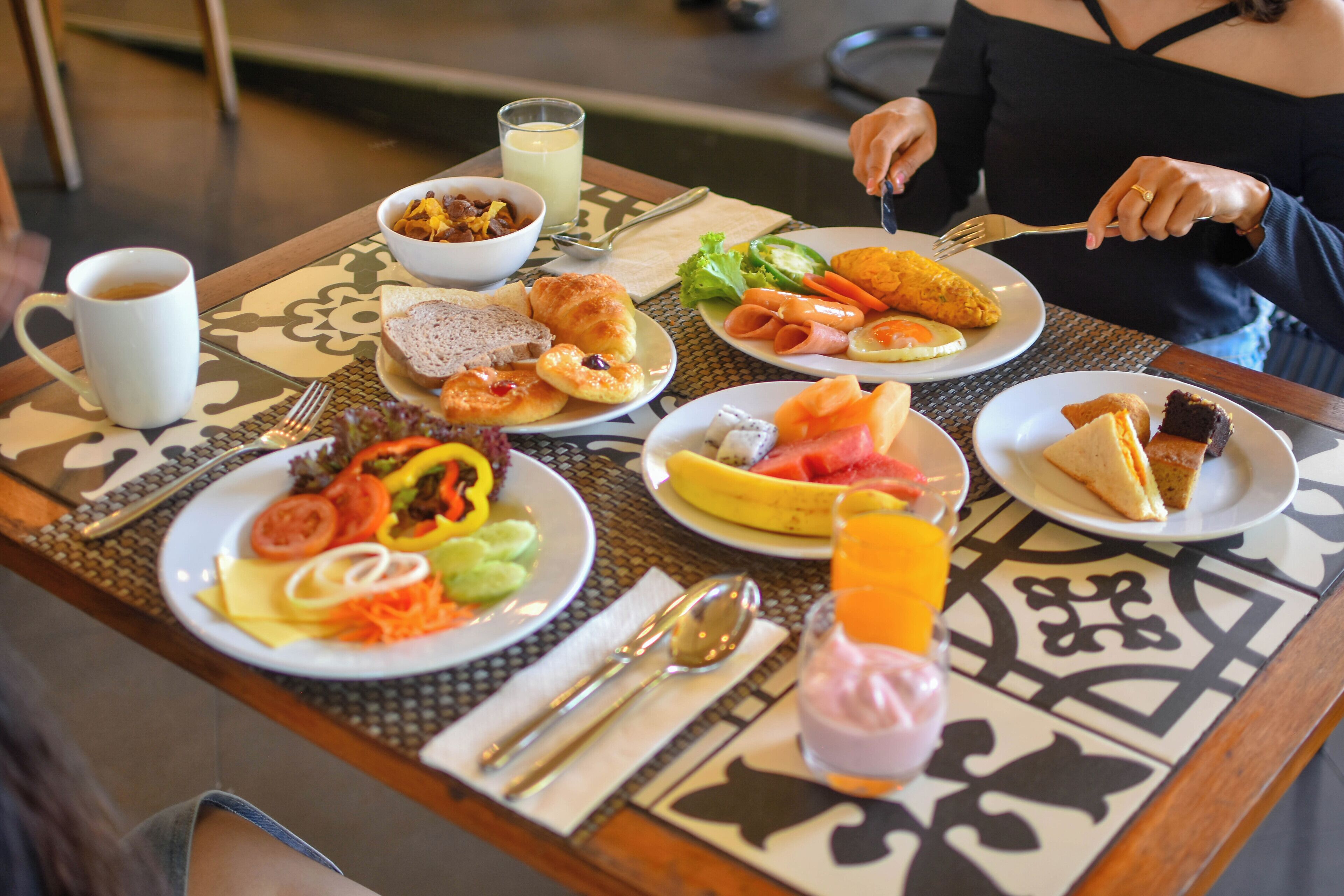A breakfast table with plates of food, utensils, and a glass of juice.