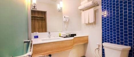 Un baño con tocador de madera, un lavabo blanco, un espejo, un perchero para toallas y una pared con azulejos azules.