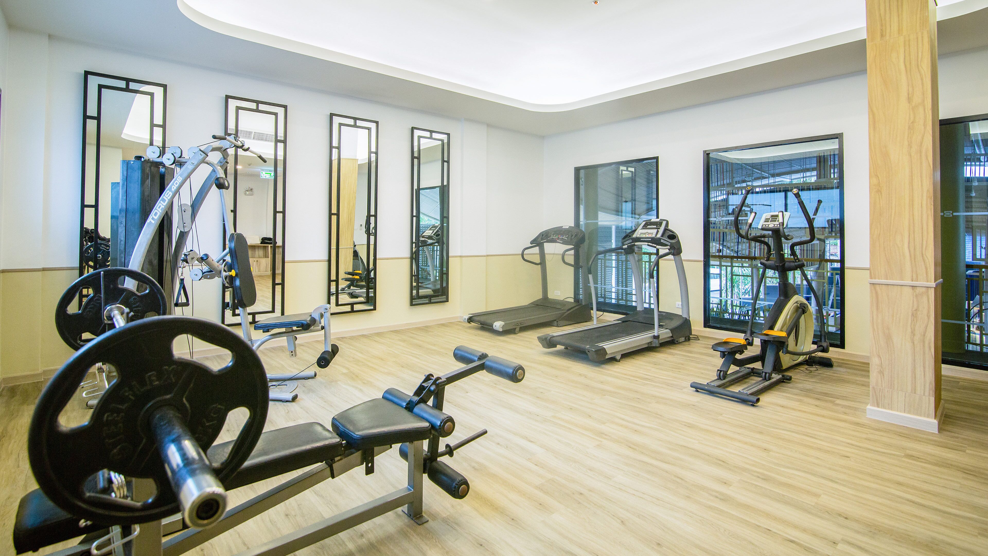 A gym with cardio machines, weightlifting equipment, and mirrors.