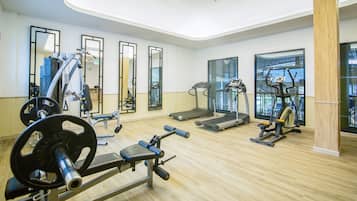 A gym with cardio machines, weightlifting equipment, and mirrors.