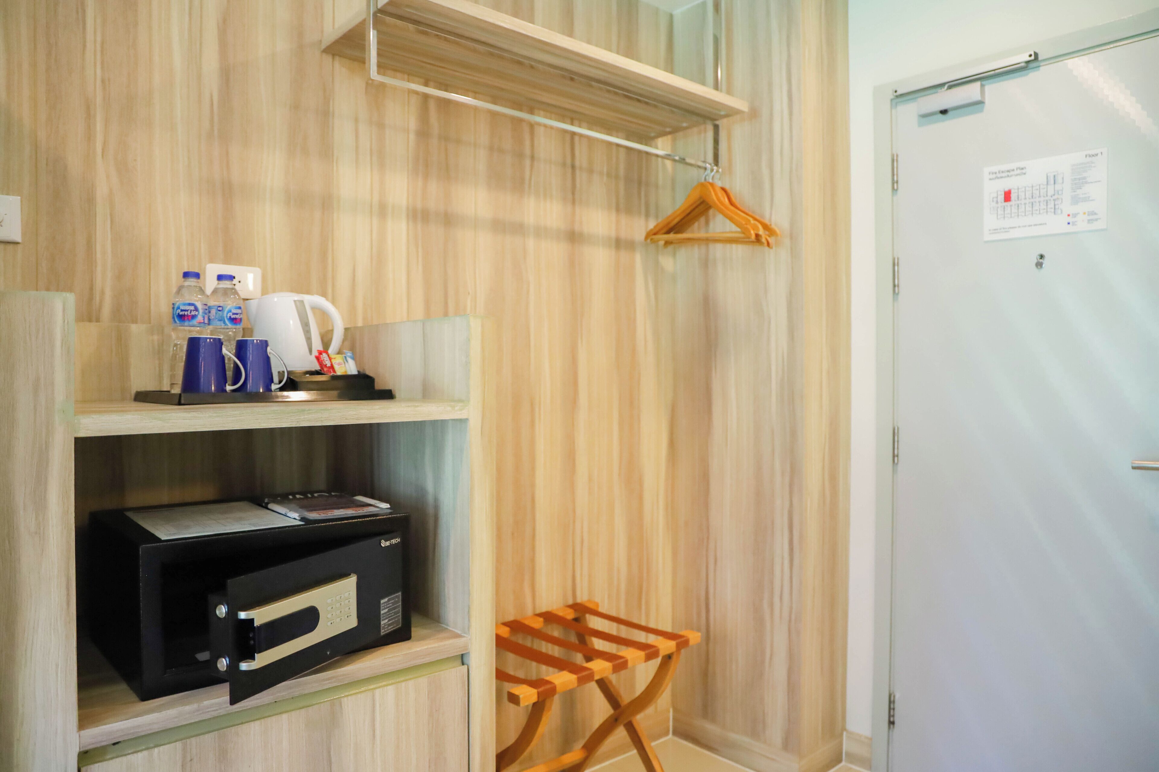 Habitación de hotel con pared de madera, microondas, cafetera y perchero de madera.