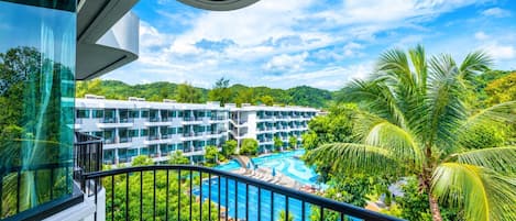 A hotel with a pool, surrounded by lush greenery and palm trees.