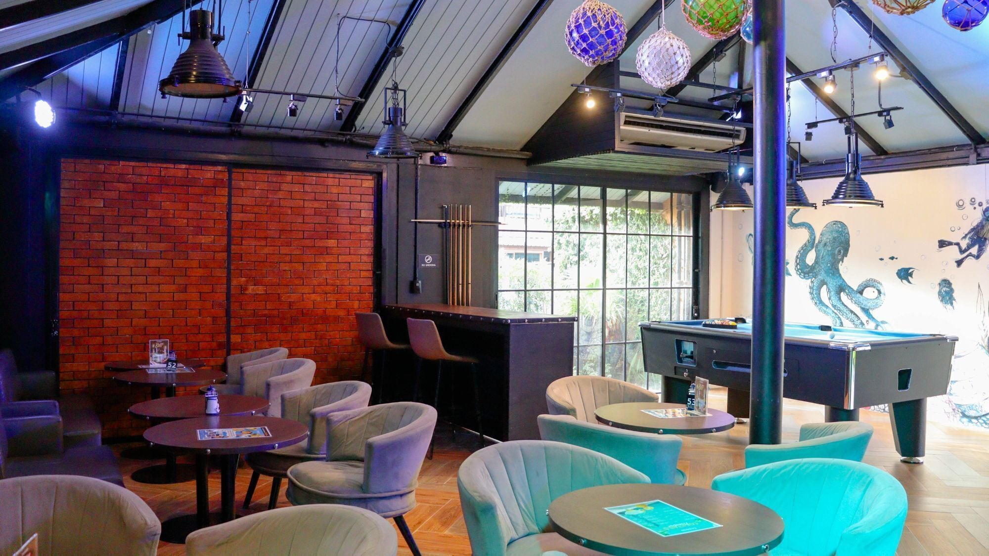 A billiards room with a brick wall, pool table, and seating area.
