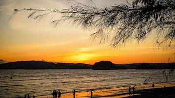 Perto da praia, areia branca, guarda-sóis, toalhas de praia