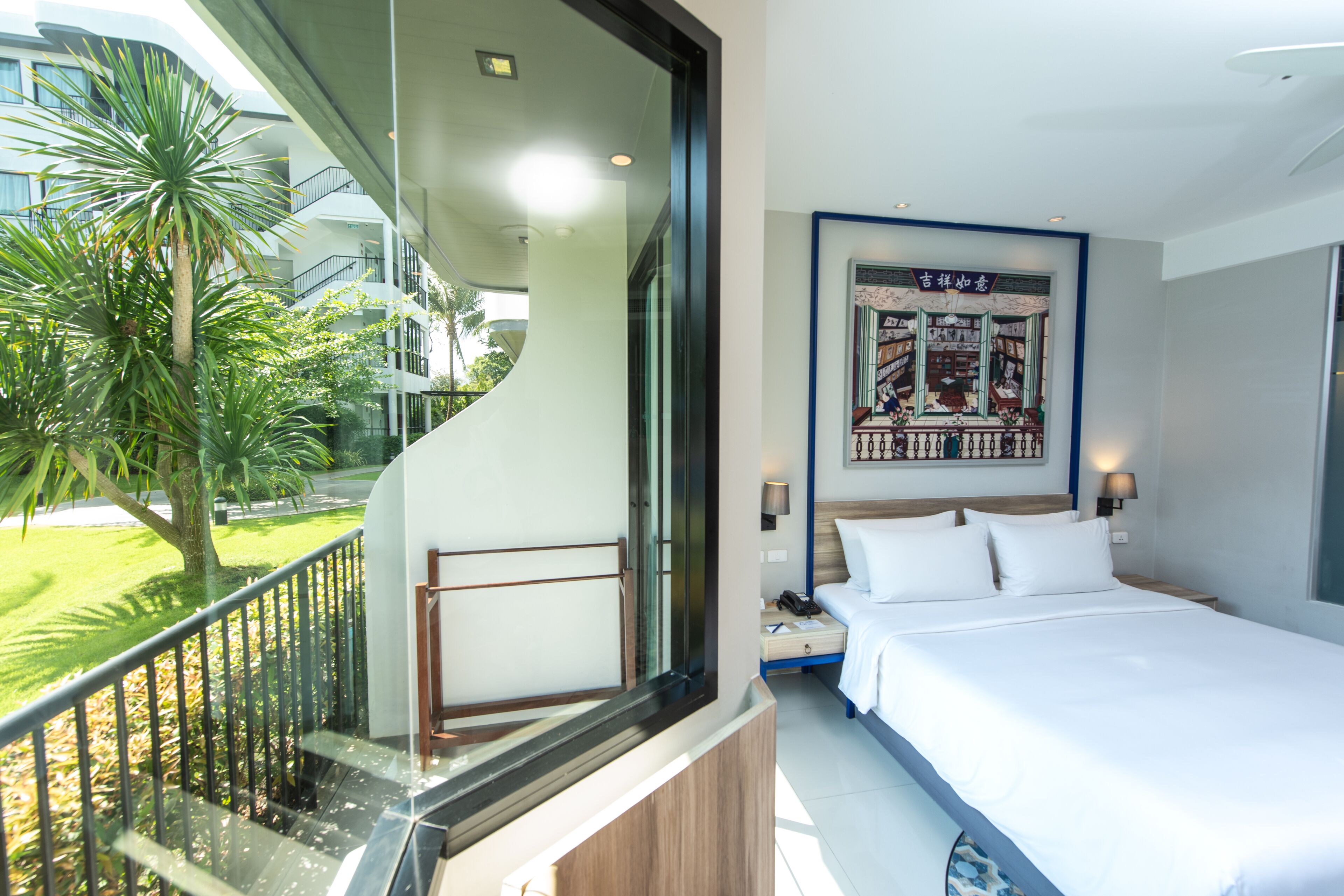 A hotel room with a balcony, a bed, a nightstand, and a wall-mounted artwork.