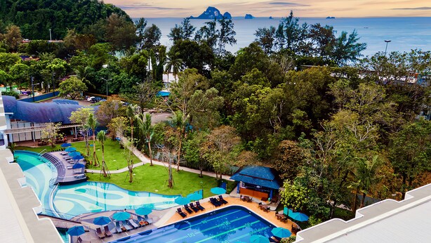 Un resort con piscina, zonas de descanso y vista al océano.
