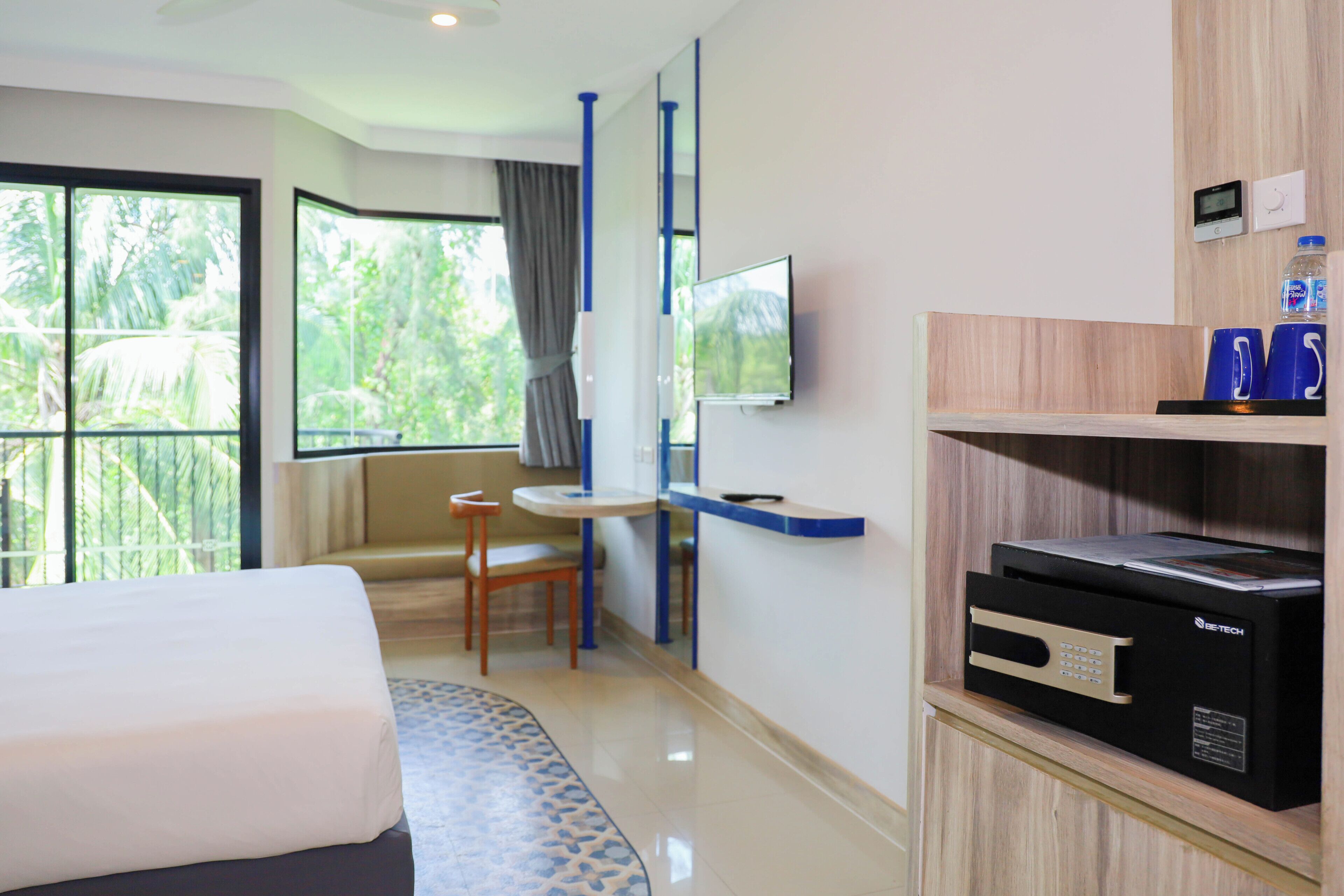 Ein Hotelzimmer mit Bett, Fernseher, Schreibtisch und Minibar.