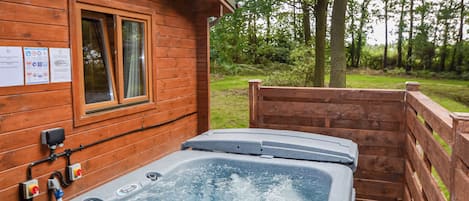 Eine Holzhütte mit Whirlpool, einem Fenster und einem Holzzaun.