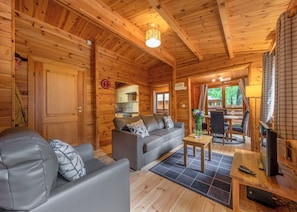 L'intérieur d'un chalet en bois, avec un canapé, une table à manger et un téléviseur.