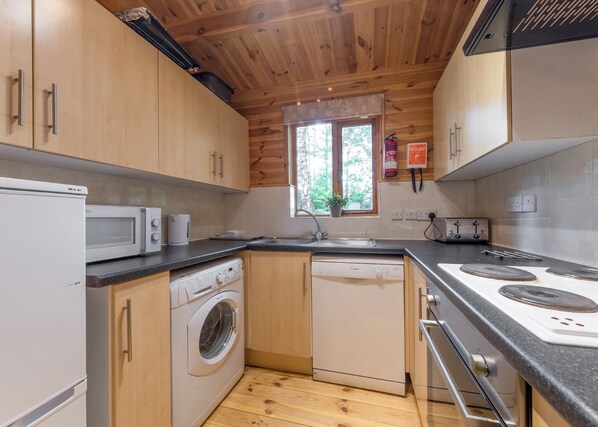 A compact kitchen with wooden cabinets, a microwave, a dishwasher, and a stove.