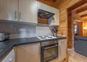 A kitchen with wooden cabinets, a stove, an oven, and a toaster.