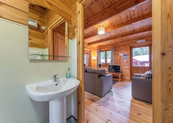 L’intérieur d’un chalet en bois comprend une salle de bain, un canapé, un téléviseur et un coin repas.