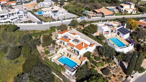 Vista aérea de una zona residencial con casas modernas, una piscina y un jardín cuidado.