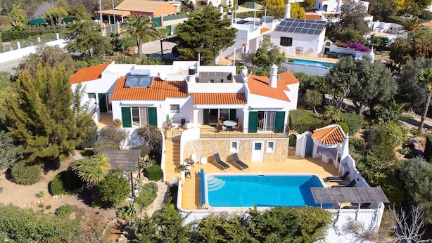 Propiedad residencial con piscina, varios edificios y vegetación circundante.