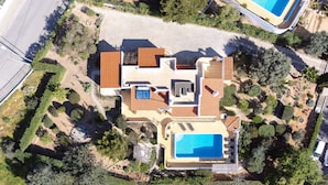 Vista aérea de una casa moderna con piscina, varias terrazas y jardines ajardinados.