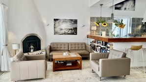 A living room with a fireplace, a sofa set, a coffee table, and a bookshelf.
