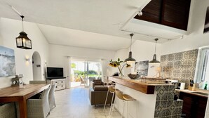 A spacious kitchen with a dining area, a TV, and a view to the outside.