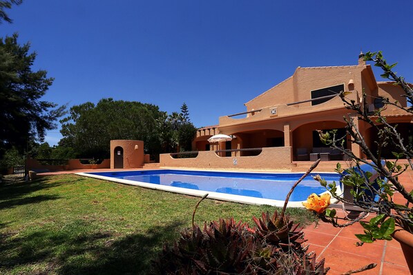 A poolside view of a house with a swimming pool, a patio area, and a garden with cacti and a flower. - Casa Monte Novo, villa with private pool near the beaches and Carvoeiro (Benagil)