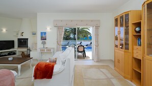 A living room with a television, sofa, and wooden cabinet. - Wonderful holiday villa with airco, heatable pool + jacuzzi on golf development (Carvoeiro)