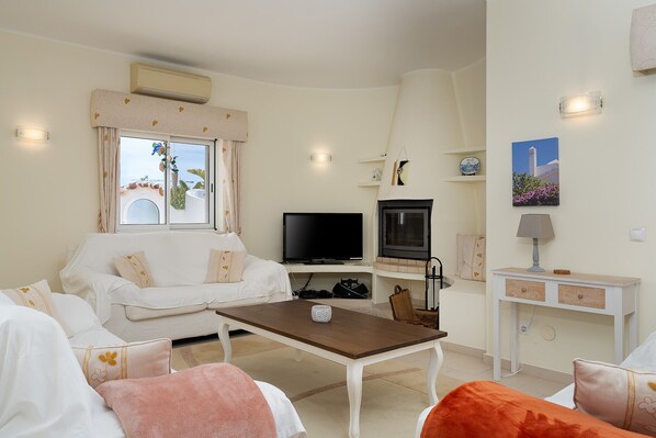 A living room with a sofa, a coffee table, a TV, and a fireplace. - Wonderful holiday villa with airco, heatable pool + jacuzzi on golf development (Carvoeiro)