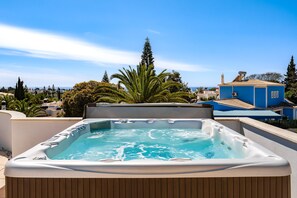 A hot tub on a rooftop with a clear view of the surrounding buildings and trees. - Wonderful holiday villa with airco, heatable pool + jacuzzi on golf development (Carvoeiro)