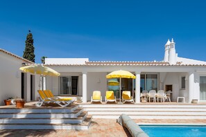 Un edificio blanco con piscina, zona de estar al aire libre y una torre con campanas.