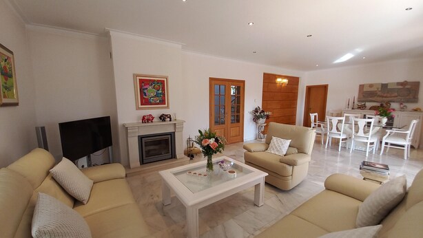Una sala de estar con chimenea, sofás, una mesa de centro y un comedor con sillas.