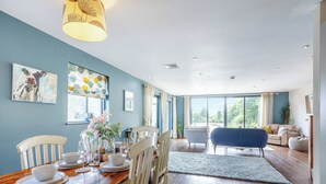 Comedor con una mesa de madera preparada para cuatro personas, rodeada de sillas blancas.