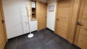 Un pasillo con puertas de madera, una pared blanca y una lámpara de pie.