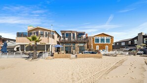 A beachfront property with a pool, outdoor seating, and a beach view.