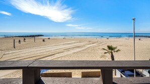 A beach with a clear sky, a palm tree, and a lifeguard tower. - 3 Bedroom Oceanfront Home on 41st St (Newport Beach)