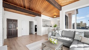 A spacious living area with a wooden ceiling, a gray sofa set, and a view of the city through large windows. - 3 Bedroom Oceanfront Home on 41st St (Newport Beach)