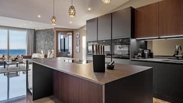 A modern kitchen with a large island, dark wood cabinets, and pendant lighting.