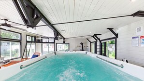 Ein Innenpool mit klarem Wasser, umgeben von Fenstern und einer Holzzieldecke.