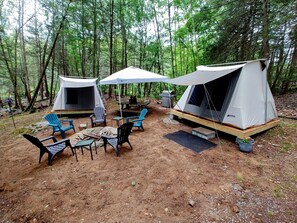 Two tents set up in a forest with a table and chairs in front. - Campers Paradise, cozy tents, hot tub, free EV charger. Pet friendly (Dover Plains)