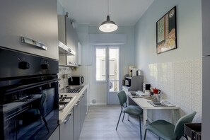 A modern kitchen with a dining area, a view through a glass door, and a kitchen island.