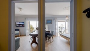 Huone, jossa on ruokapöytä, tuoleja, televisio ja näkymä ulos.