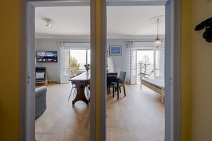 A room with a dining table, chairs, a TV, and a view of the outdoors.