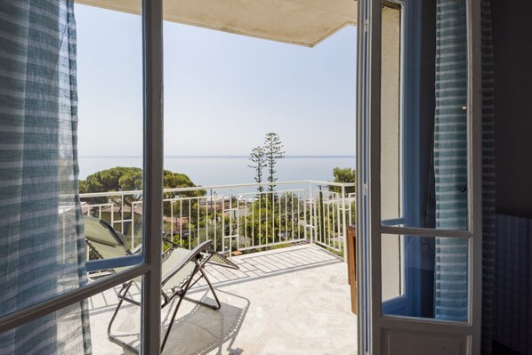 Un balcón con vistas al mar, una silla y una mesa.