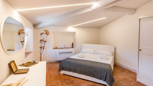Un dormitorio con cama, mesita de noche, espejo y aire acondicionado instalado en la pared.