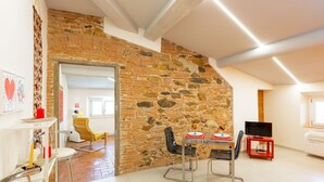Un comedor con pared de piedra, una mesa con sillas, un televisor y un atril rojo.