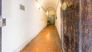 Un pasillo estrecho con piso de baldosas, una puerta con picaporte de latón y un letrero en la pared.