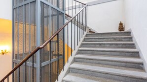 Una escalera con barandillas de metal y una protección de malla, que conduce a un piso superior.