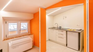 Una cocina compacta con horno integrado, un lavamanos y un refrigerador pequeño.